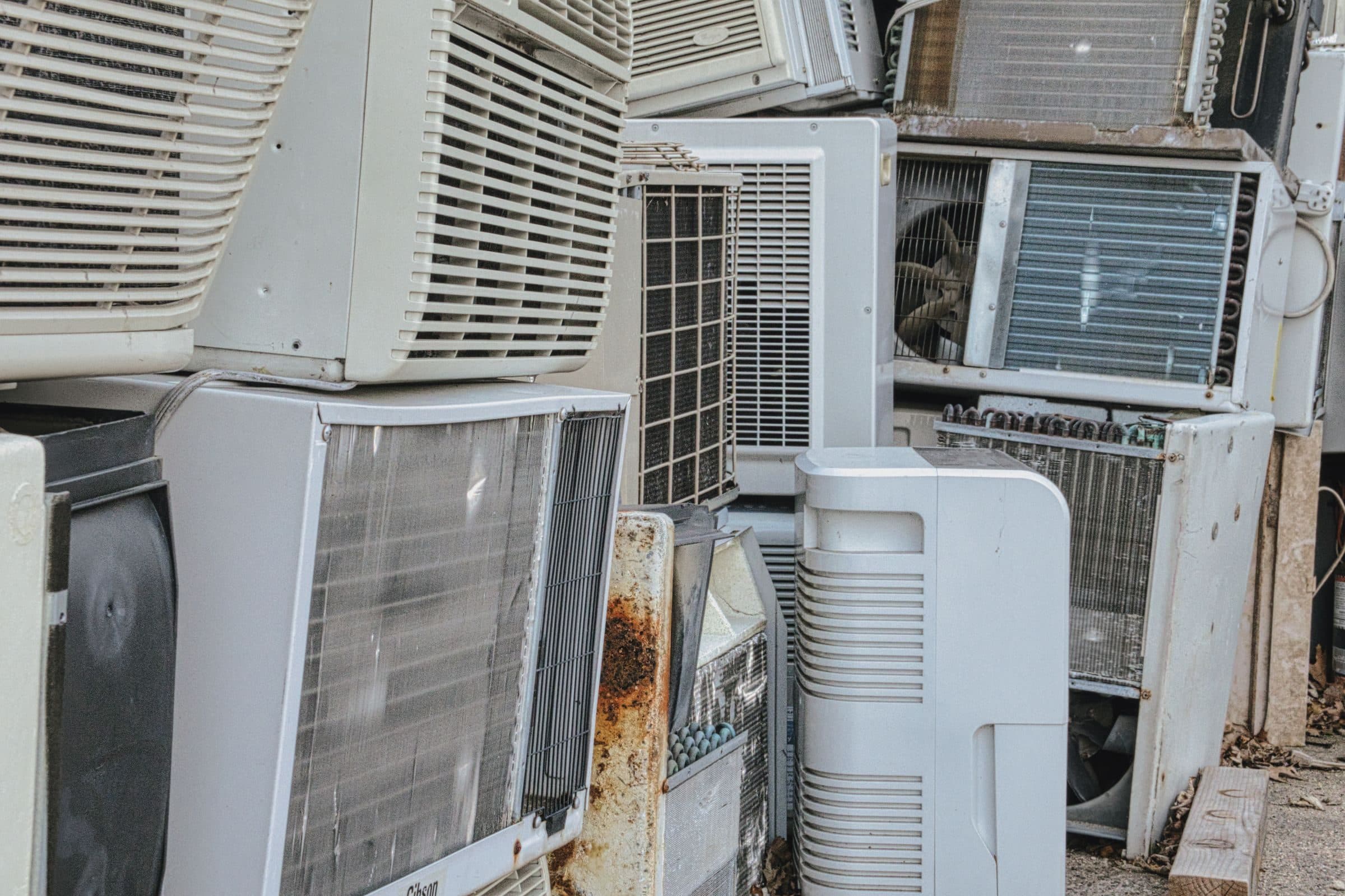 Old window and portable air conditioners stacked outdoors, waiting to be recycled