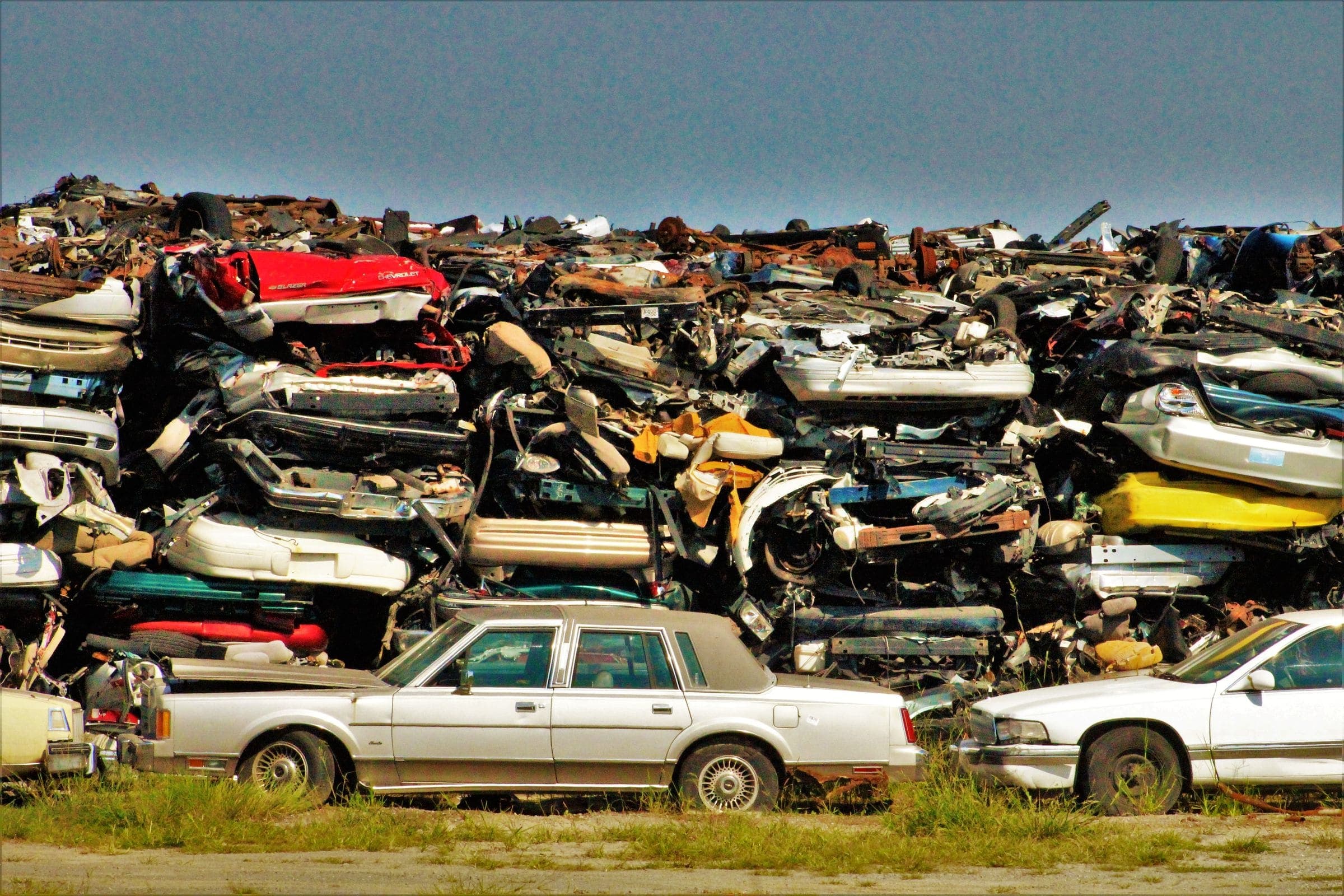 Rows of crushed and stacked scrap cars in an outdoor junkyard