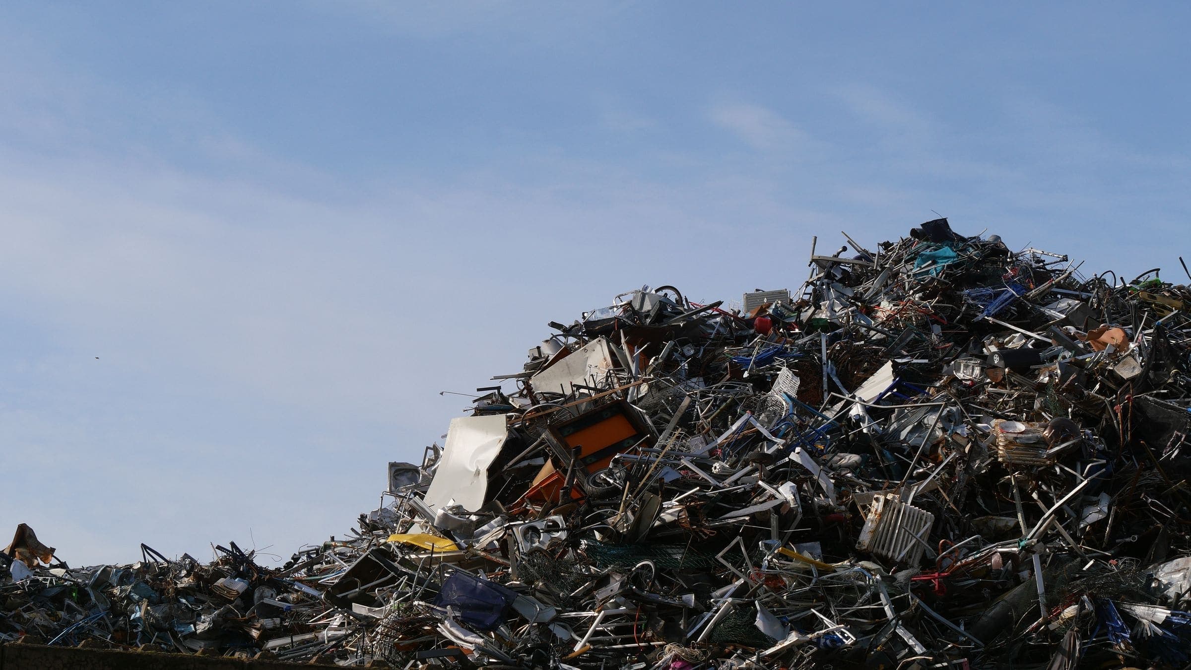 Scrap metal pile A large mound of mixed scrap metal in a recycling yard under a blue sky