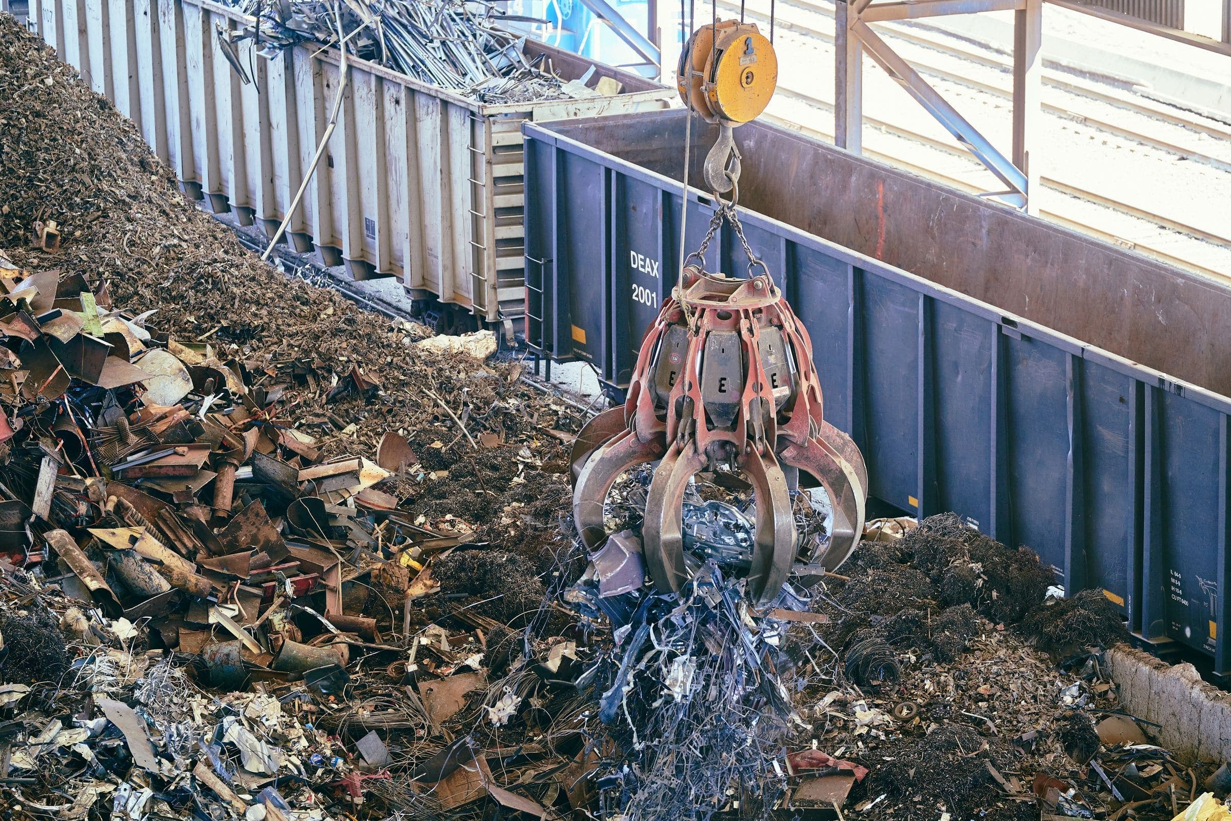 Grab loading scrap metal A crane's orange-peel grab dropping shredded scrap metal onto a pile beside open wagons