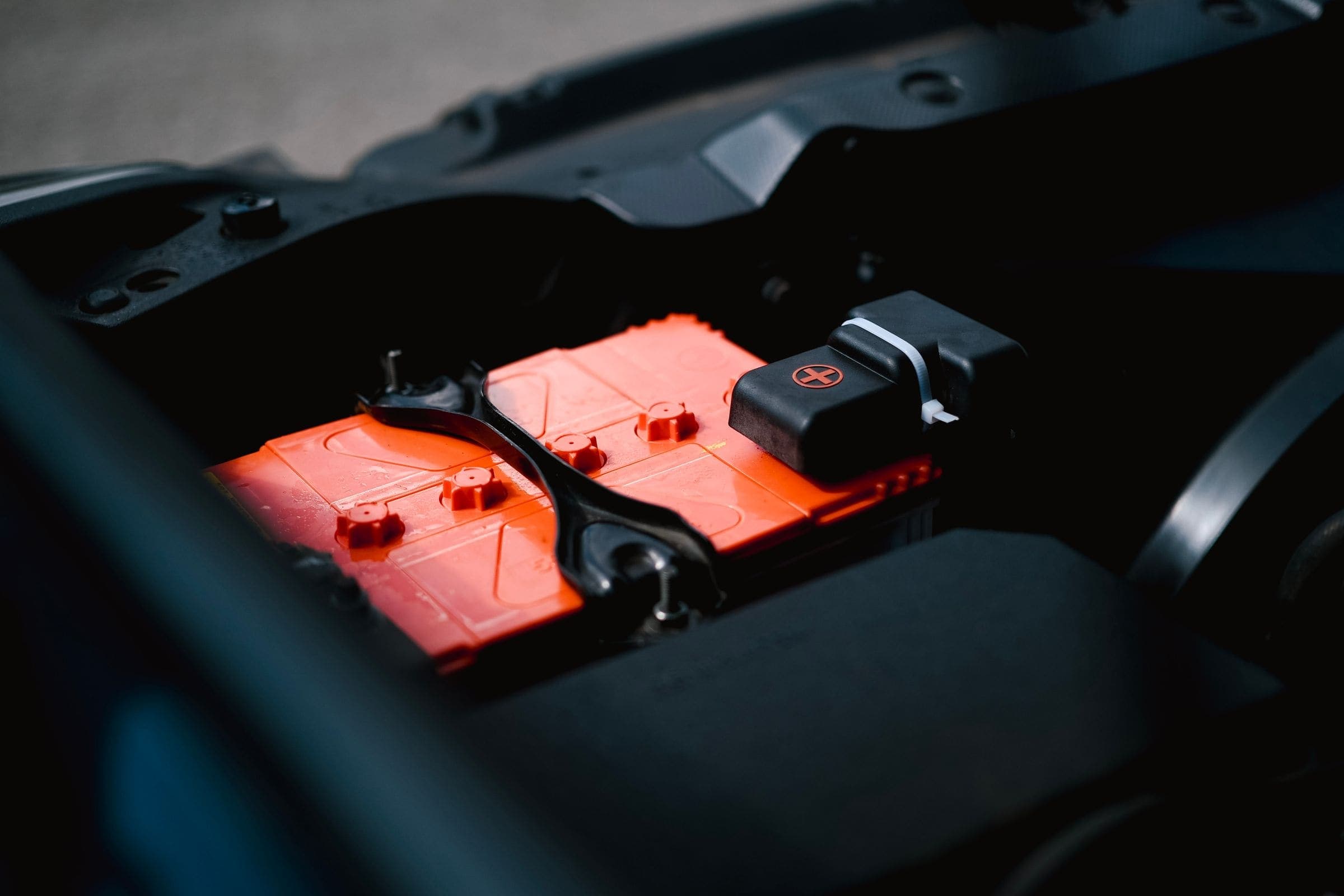 Car battery in engine bay An orange car battery in a dark engine bay