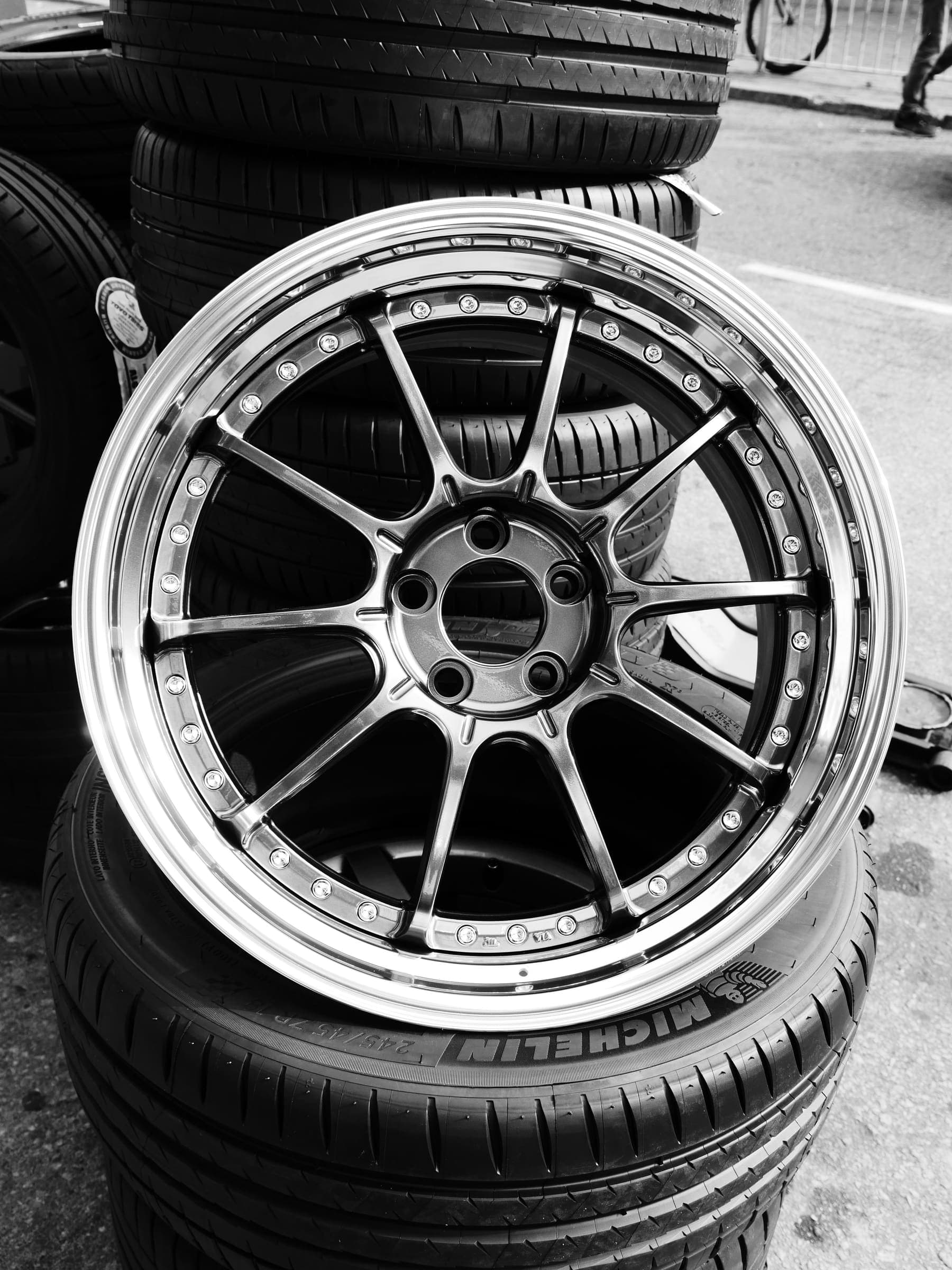 Alloy rim on old tyres A polished alloy wheel leaning on a stack of used car tyres