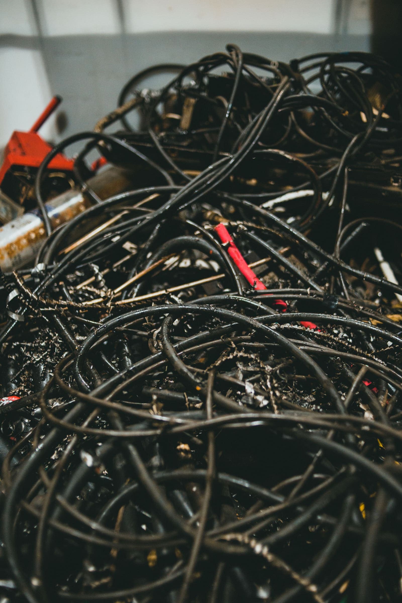 Pile of scrap cable A large tangled pile of black insulated electrical cable in a workshop
