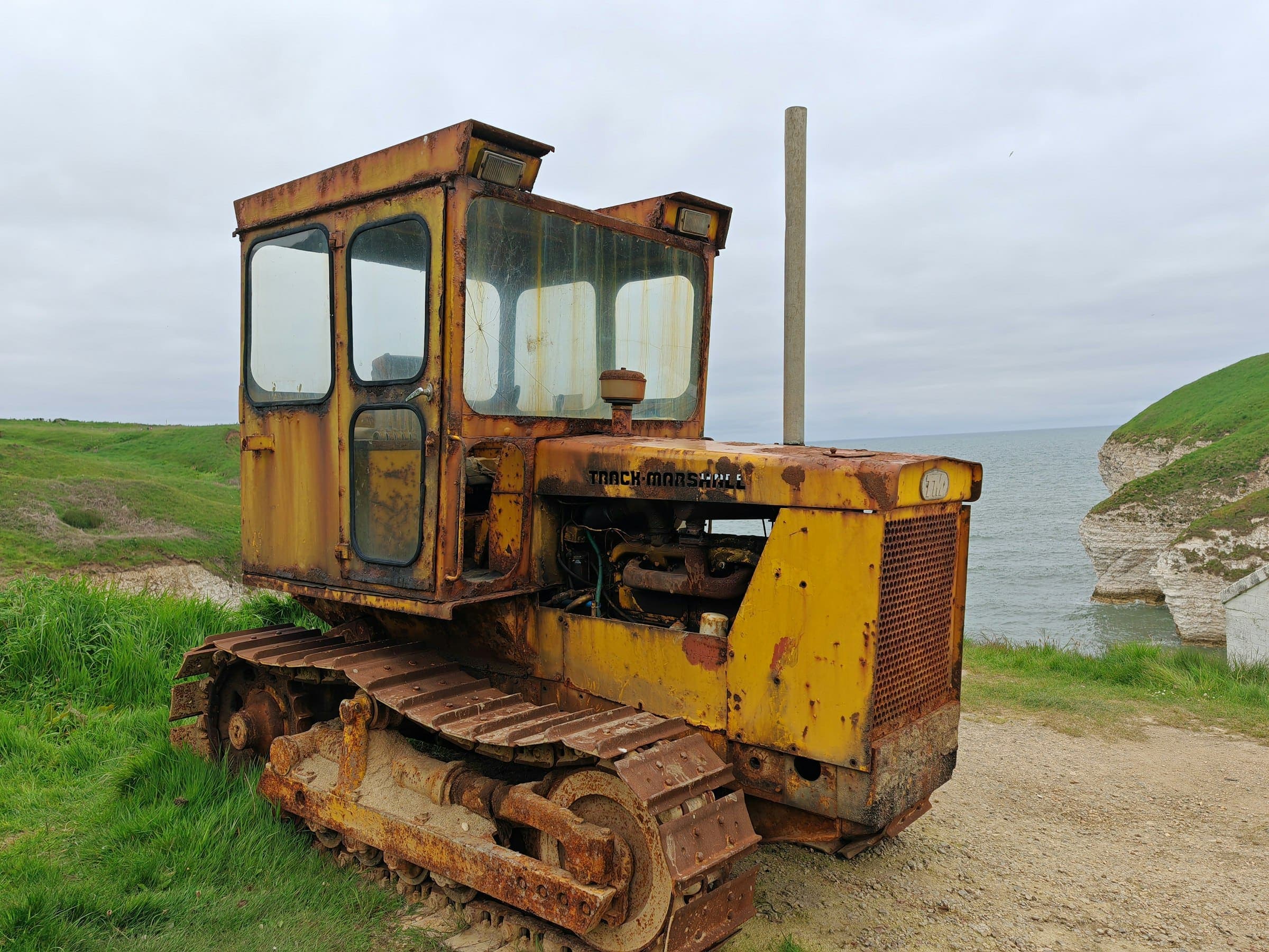 Abandoned rusty bulldozer A rusty yellow crawler bulldozer left on a grassy hilltop