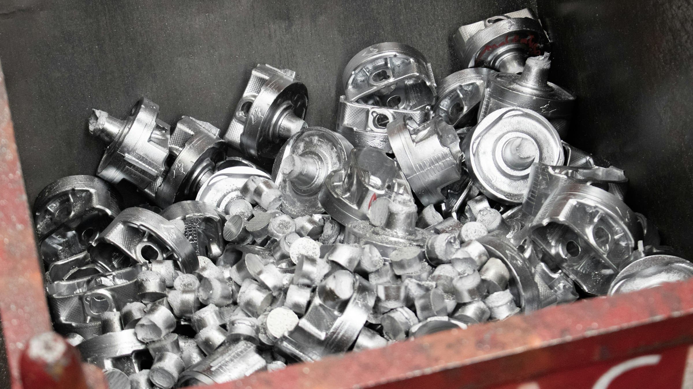 Bin of cast aluminium scrap A red scrap bin filled with silver cast metal parts and offcuts