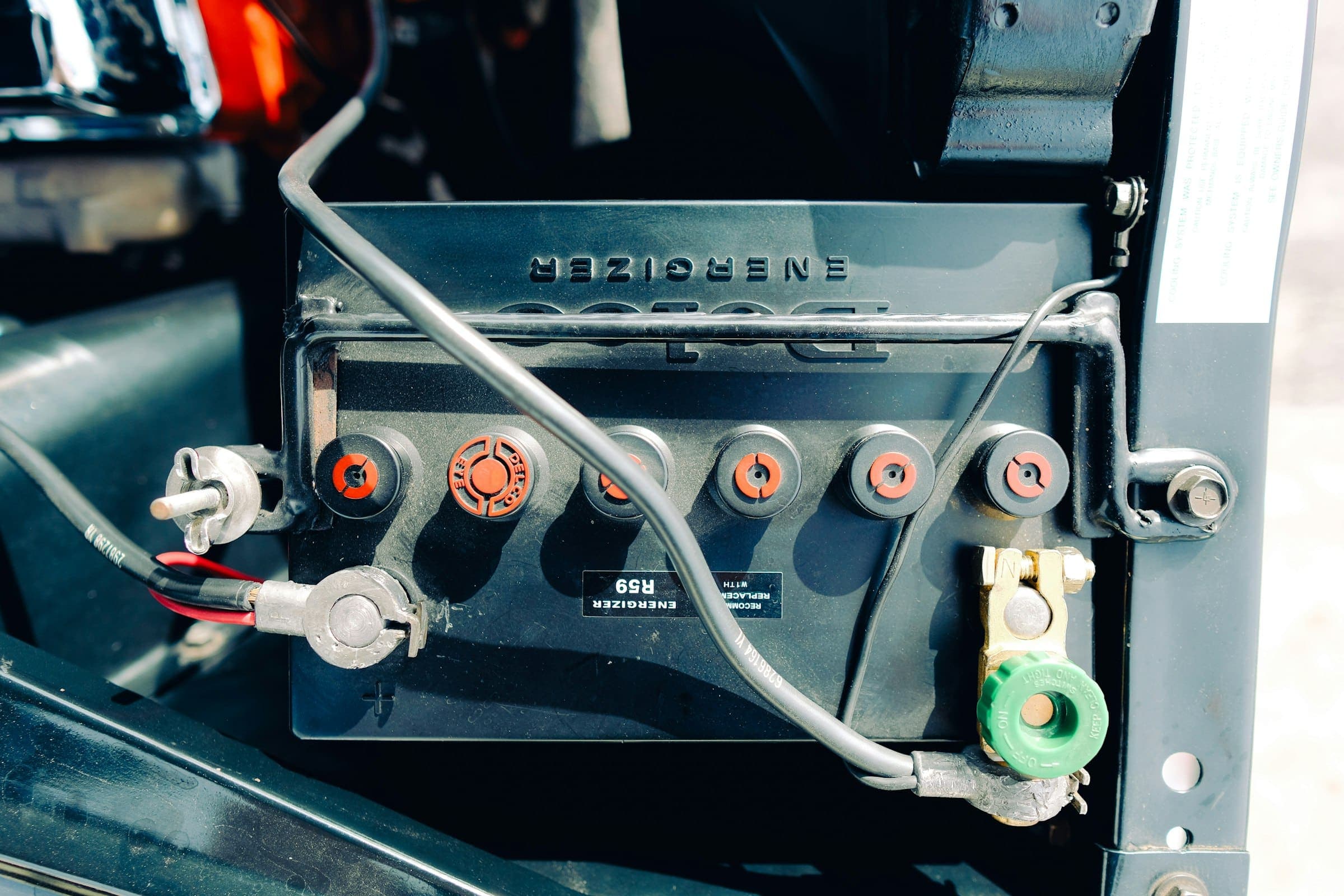 Lead-acid car battery A black lead-acid car battery with its cables connected, mounted in a car